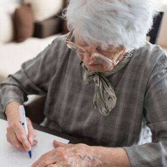 Pensionistin macht den 'Uhrentest' auf einem Blatt Papier
