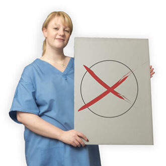 Pflegekraft hält ein großes Bild hoch auf dem ein Wahlkreuz zu sehen ist