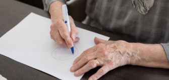Pensionistin malt die Uhr auf ein Blatt Papier
