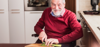 Pensionist im Rollstuhl schneidet Gemüse