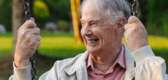 Pensionist sitzt auf Schaukel und lächelt