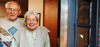 Pensionist und Pensionistin öffnen ihre Haustür