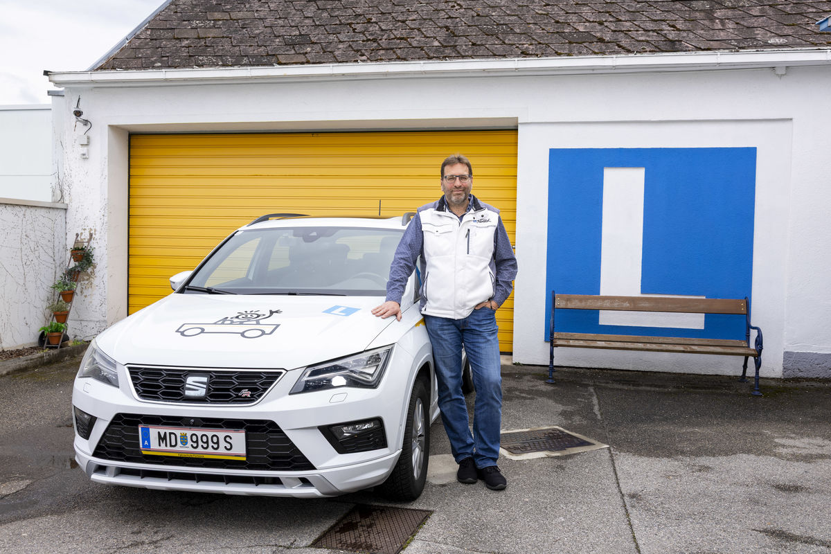 Alexander Seger lehnt an ein Auto und lächelt in die Kamera