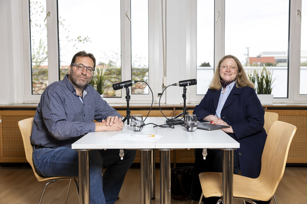 Alexander Seger und Asta Krjci-Sebesta sitzen an einem Tisch und nehmen einen Podcast auf