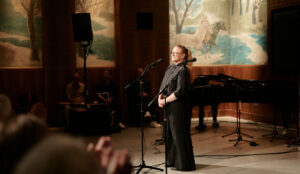 Frau steht auf der Bühne und lächelt ins Publikum