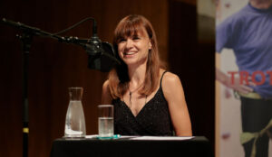 Mari Lang redet ins Mikrofon und lächelt das Publikum an