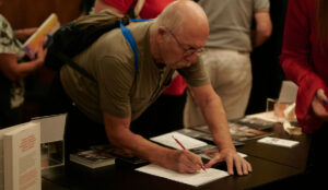 Ein Pensionist schreibt etwas auf ein Blatt Papier