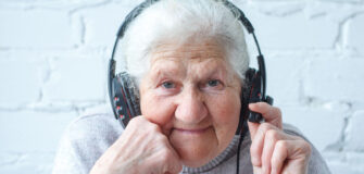 Pensionistin trägt Kopfhörer und schaut in die Kamera