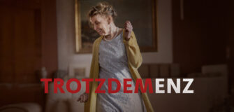 Eine ältere Frau tanzt im Wohnzimmer. Darunter ist er Schriftzug "Trotzdemenz" zu lesen.